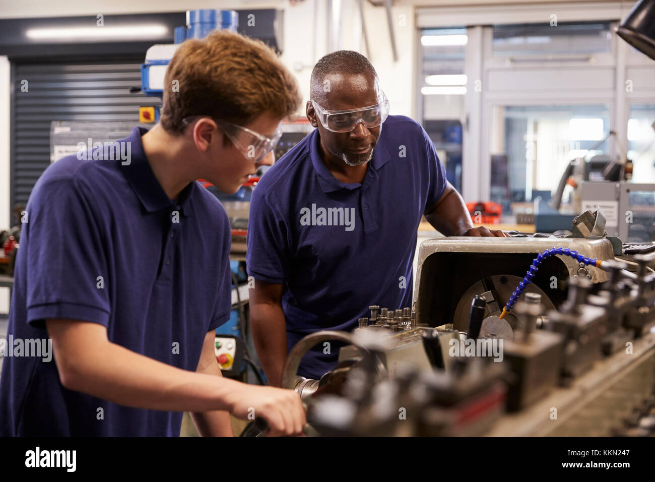Engineer Showing Teenage Apprentice How To Use Lathe Stock Photo