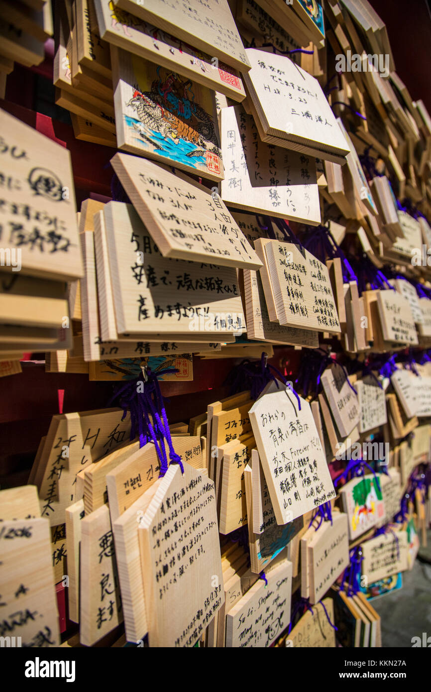 Tokyo, Japan - March 26, 2016: A wall of wooden wishing plaques. One front of ema has space for writing one wish and another front usually have decora Stock Photo