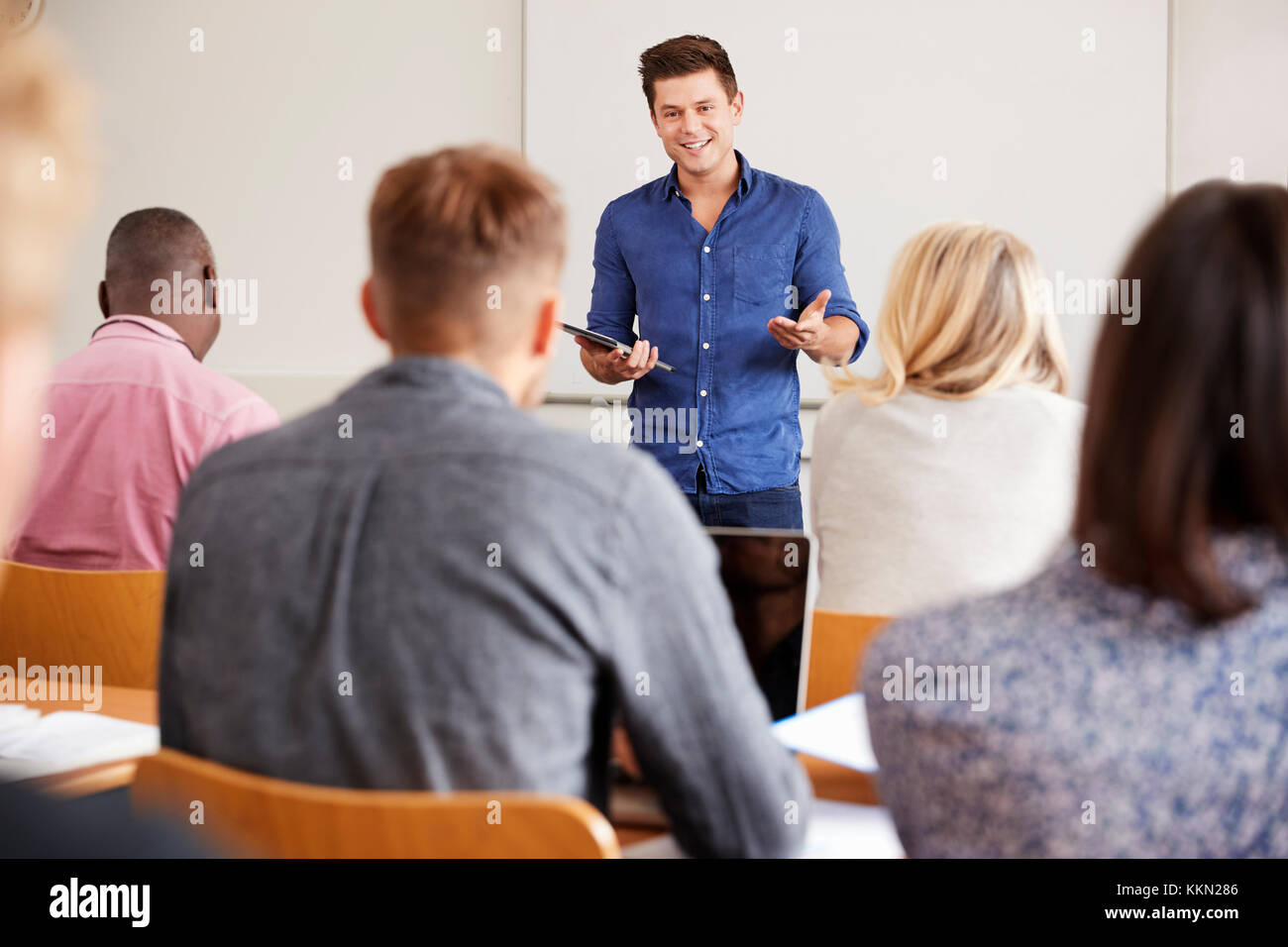 College Tutor With Digital Tablet Teaches Mature Students Stock Photo