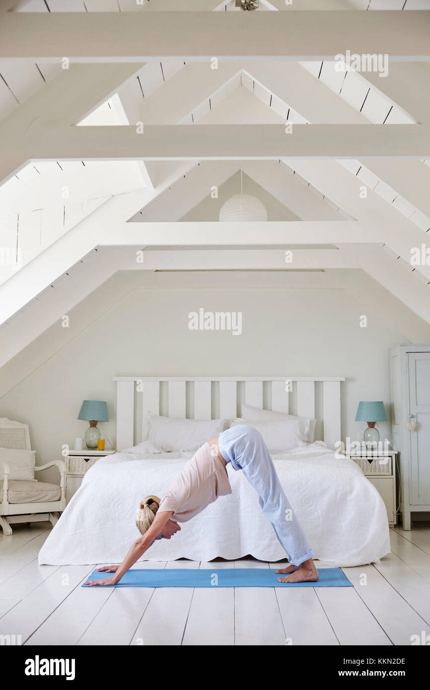 Woman At Home Starting Morning With Yoga Exercises In Bedroom Stock