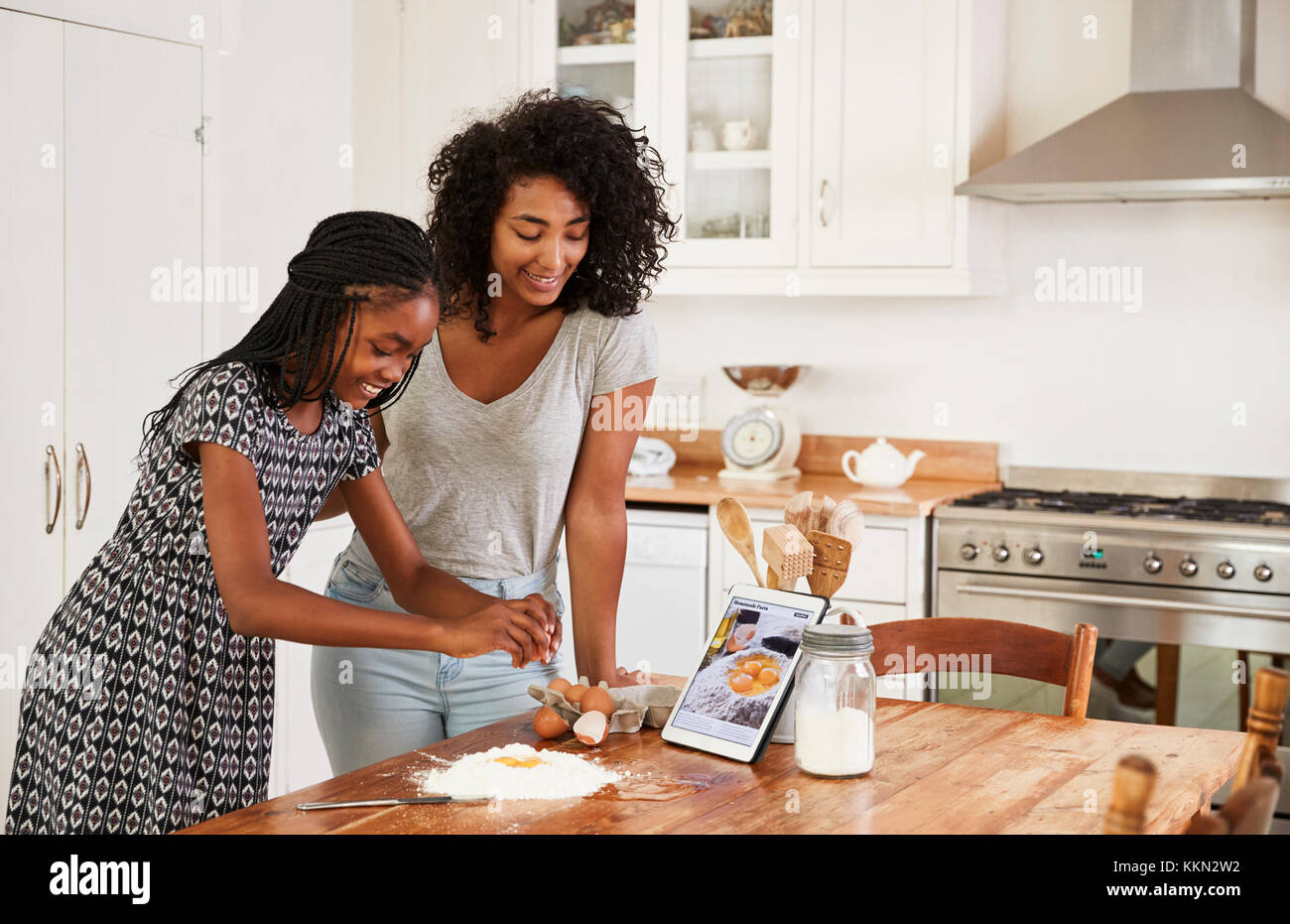 Teenage Girls Following Recipe On Digital Tablet Stock Photo