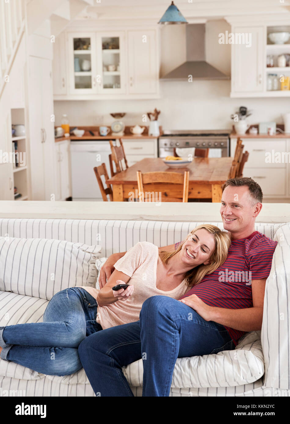 Couple Sitting On Sofa Watching Television Together Stock Photo