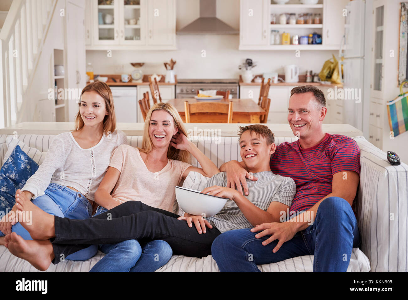 Family With Teenage Children Sitting On Sofa Watching TV Together Stock Photo
