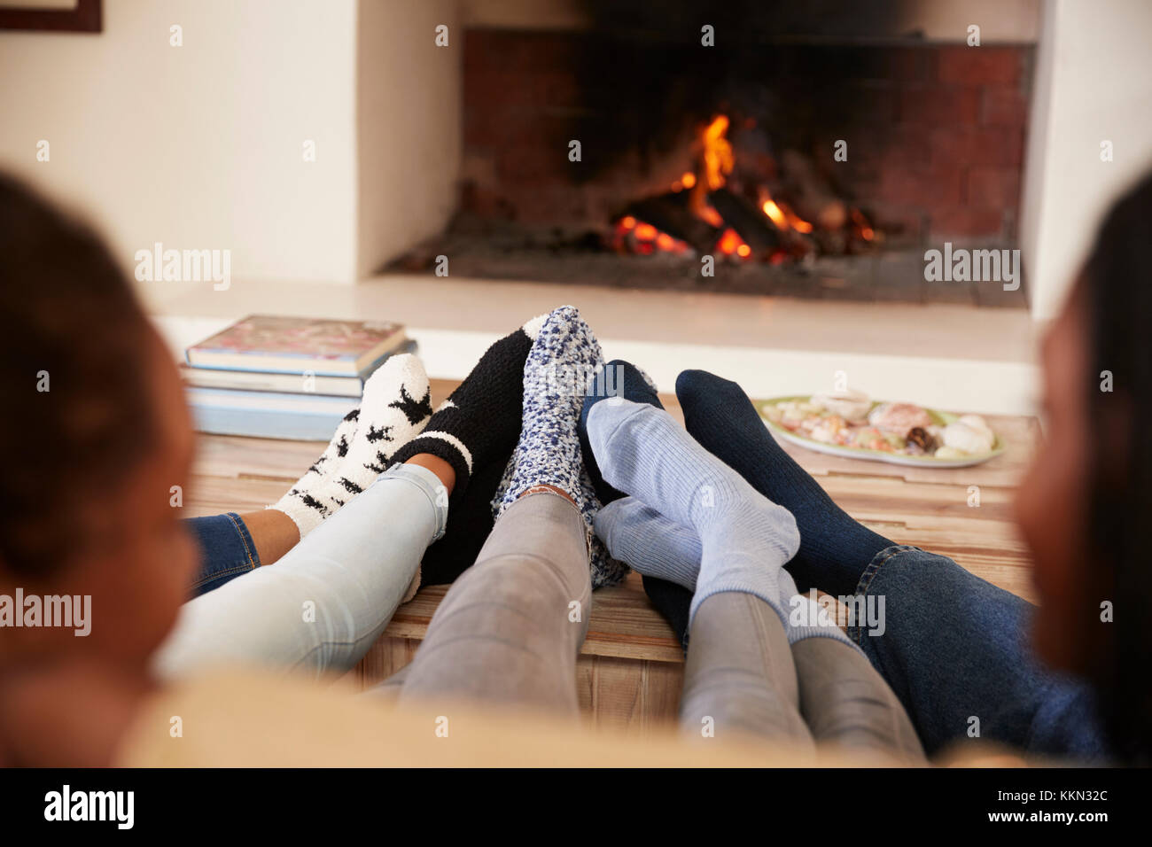 Close Up Of Feet As Family Relax Next To Open Fire Stock Photo