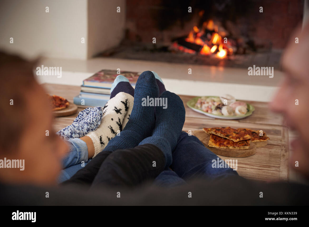 Close Up Of Feet As Family Relax Next To Open Fire Stock Photo