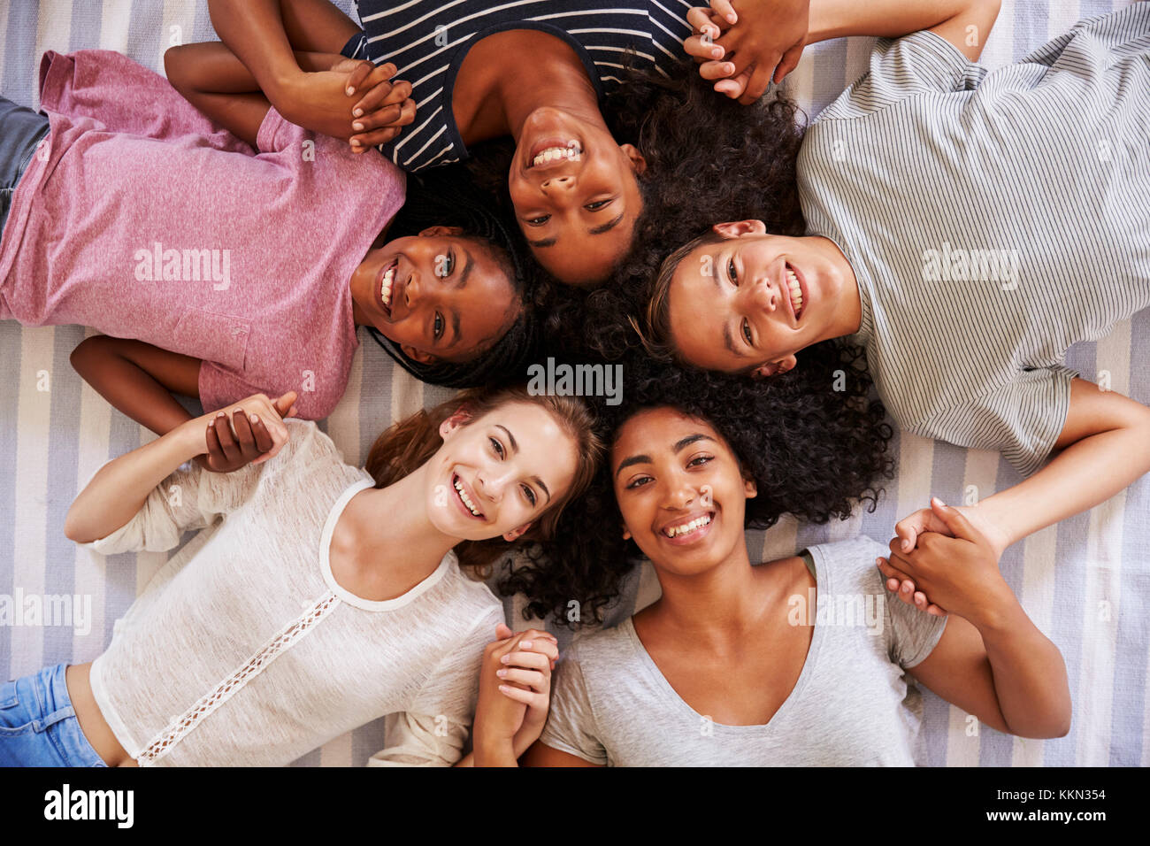 Overhead View Of Teenage Friends Lying On Bed Together Stock Photo