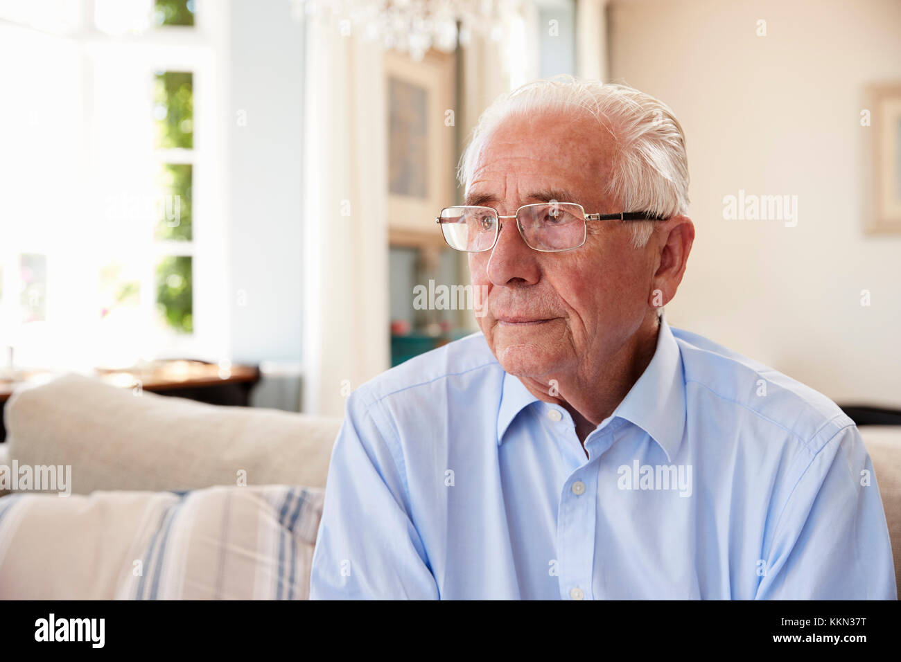 Senior Man Sitting On Sofa At Home Suffering From Depression Stock Photo