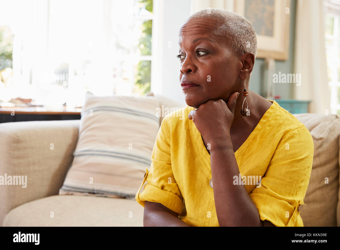 Senior Woman Sitting On Sofa At Home Suffering From Depression Stock Photo