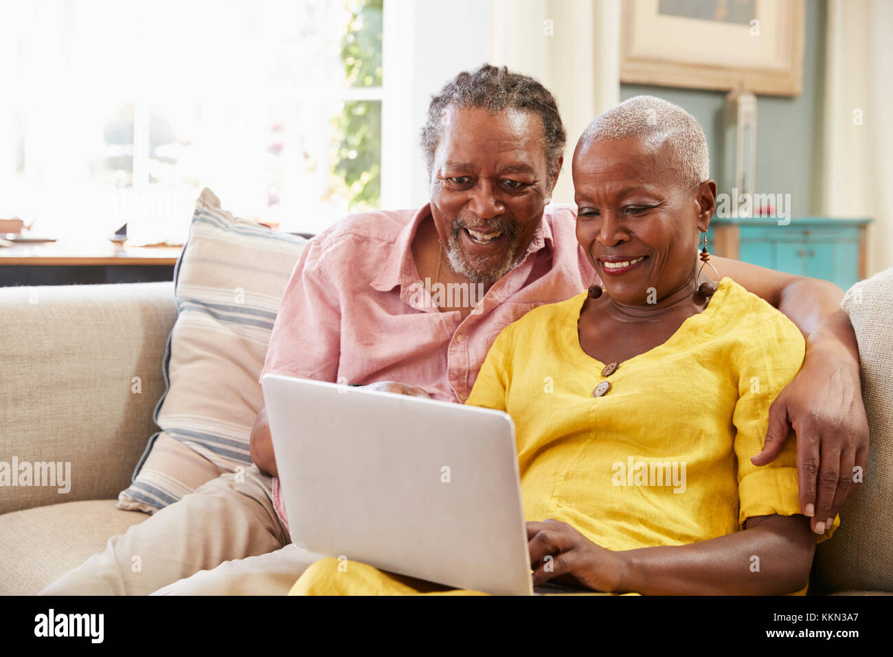 Senior Couple Sitting On Sofa Using Laptop At Home Together Stock Photo