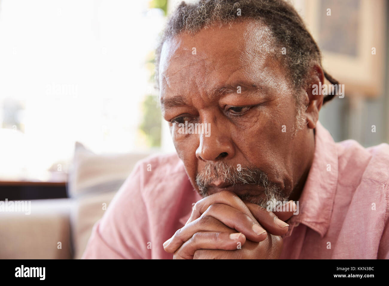 Senior Man Sitting On Sofa At Home Suffering From Depression Stock Photo