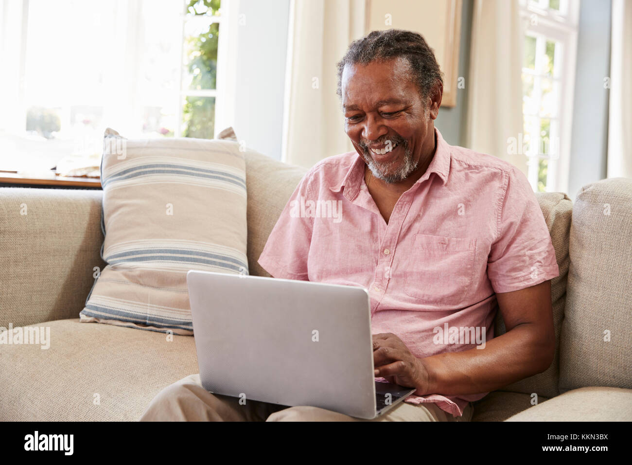 Senior Man Sitting On Sofa Using Laptop At Home Together Stock Photo