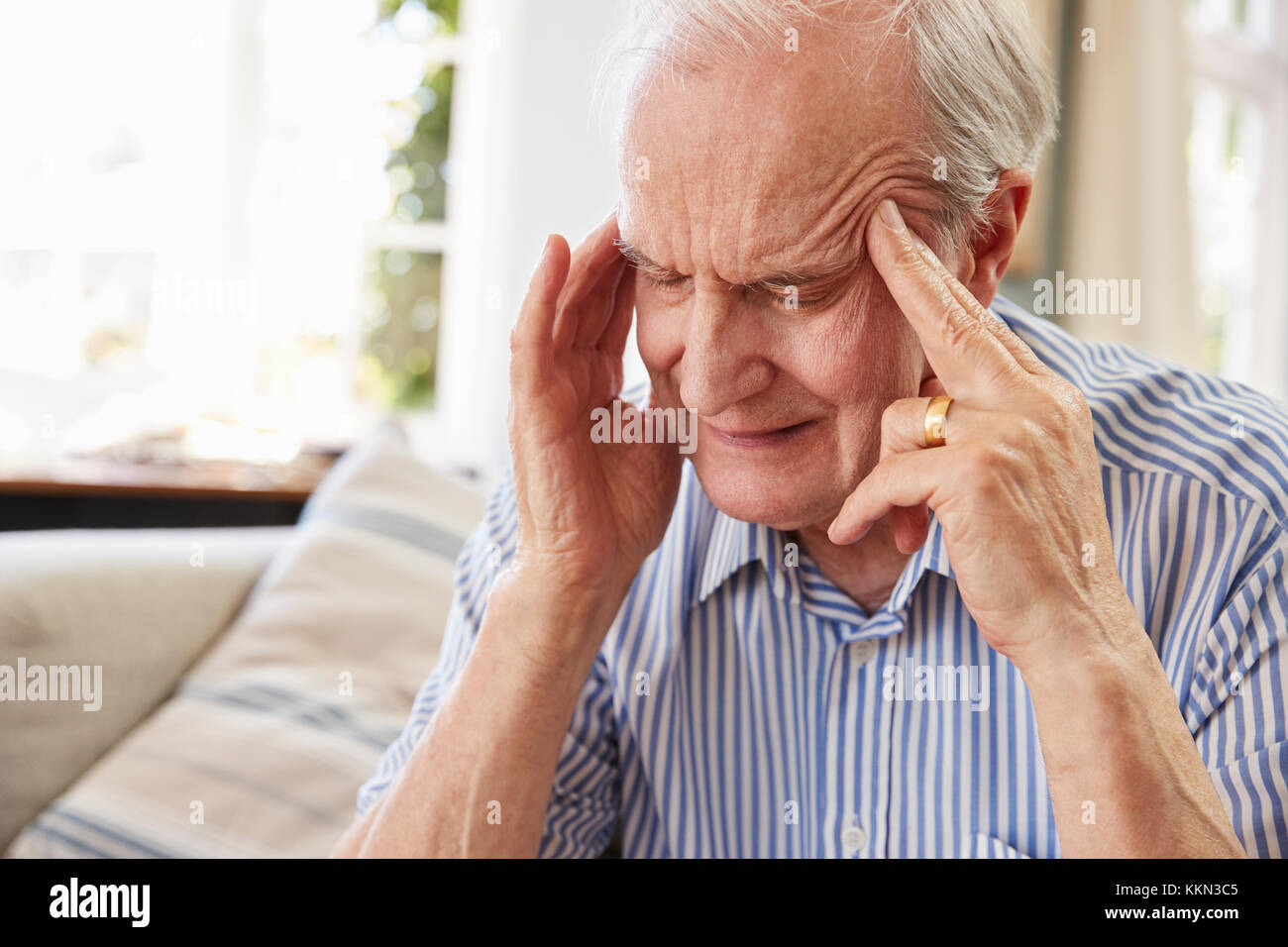 Senior Man Sitting On Sofa At Home Suffering From Depression Stock Photo