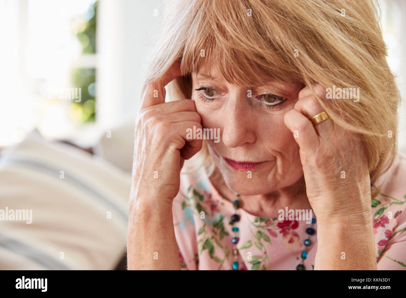 Senior Woman Sitting On Sofa At Home Suffering From Depression Stock Photo