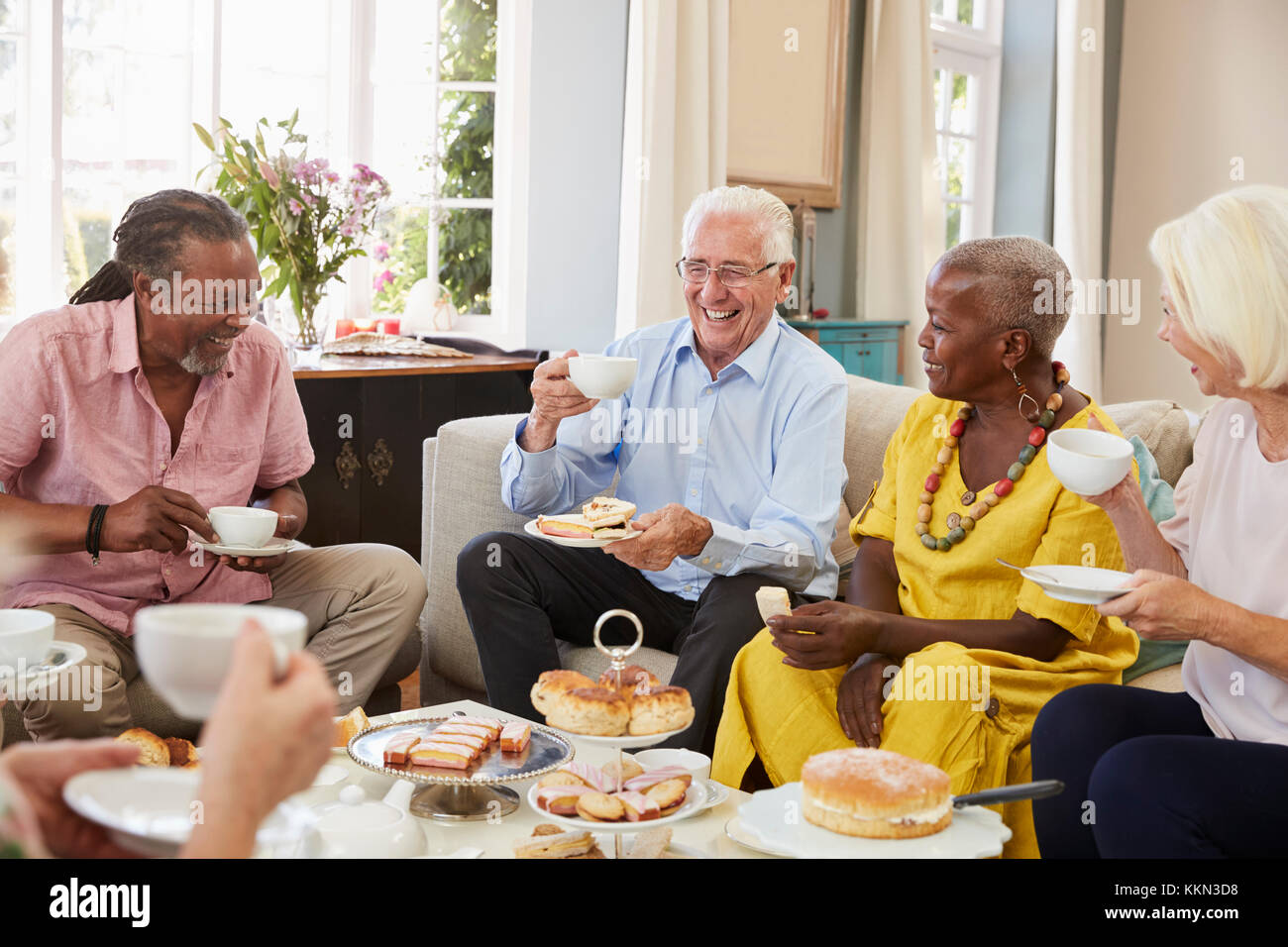 Group Of Senior Friends Enjoying Afternoon Tea At Home Together Stock Photo