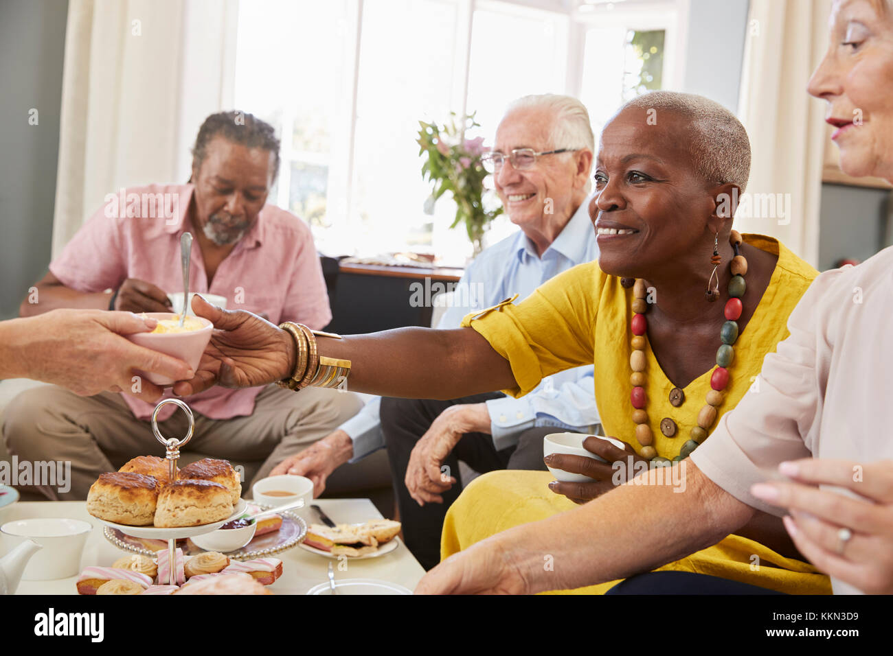 Group Of Senior Friends Enjoying Afternoon Tea At Home Together Stock Photo