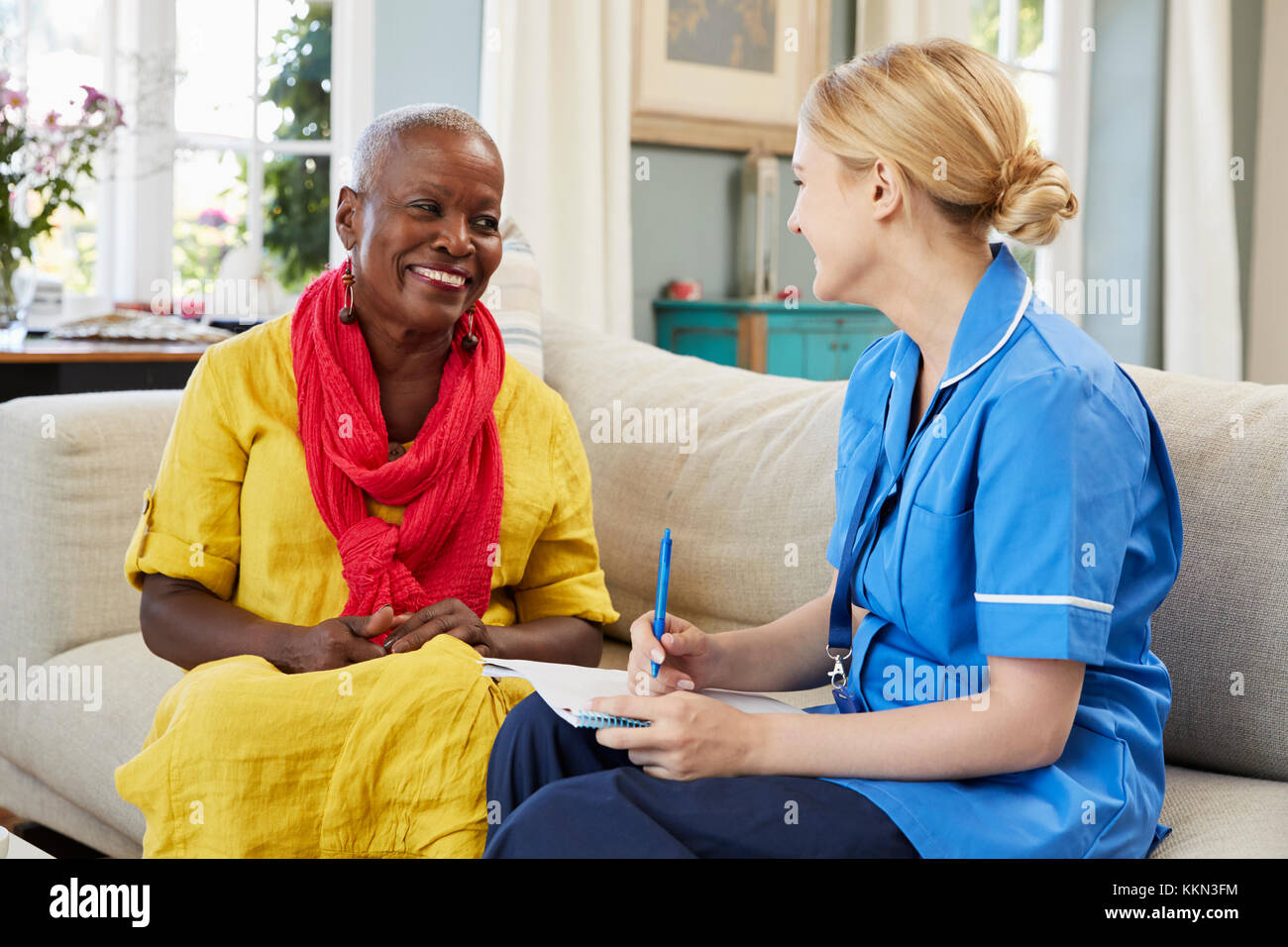 Female Community Nurse Visits Senior Woman At Home Stock Photo