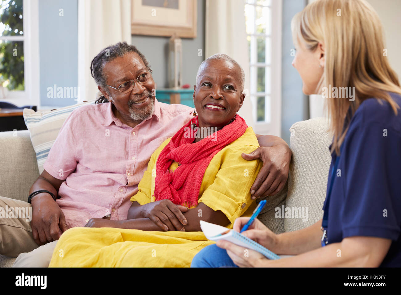Female Support Worker Visits Senior Couple At Home Stock Photo