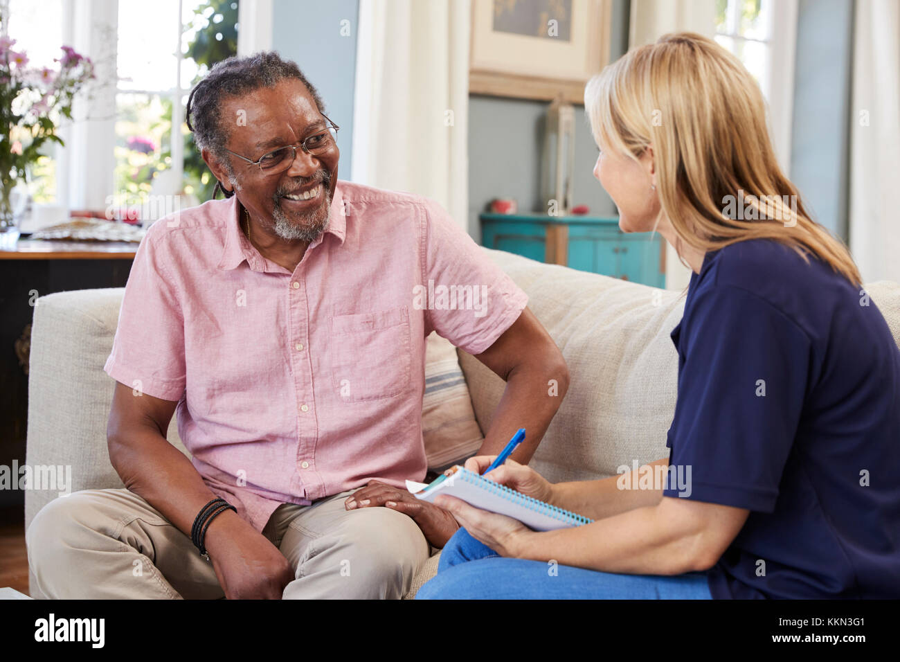 Female Support Worker Visits Senior Man At Home Stock Photo