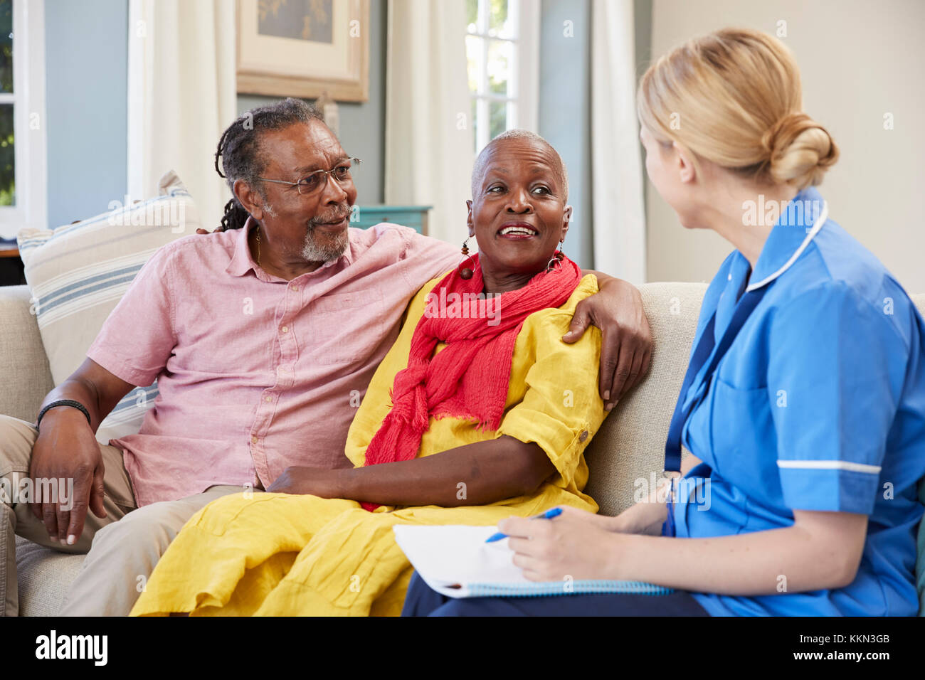 Female Community Nurse Visits Senior Couple At Home Stock Photo