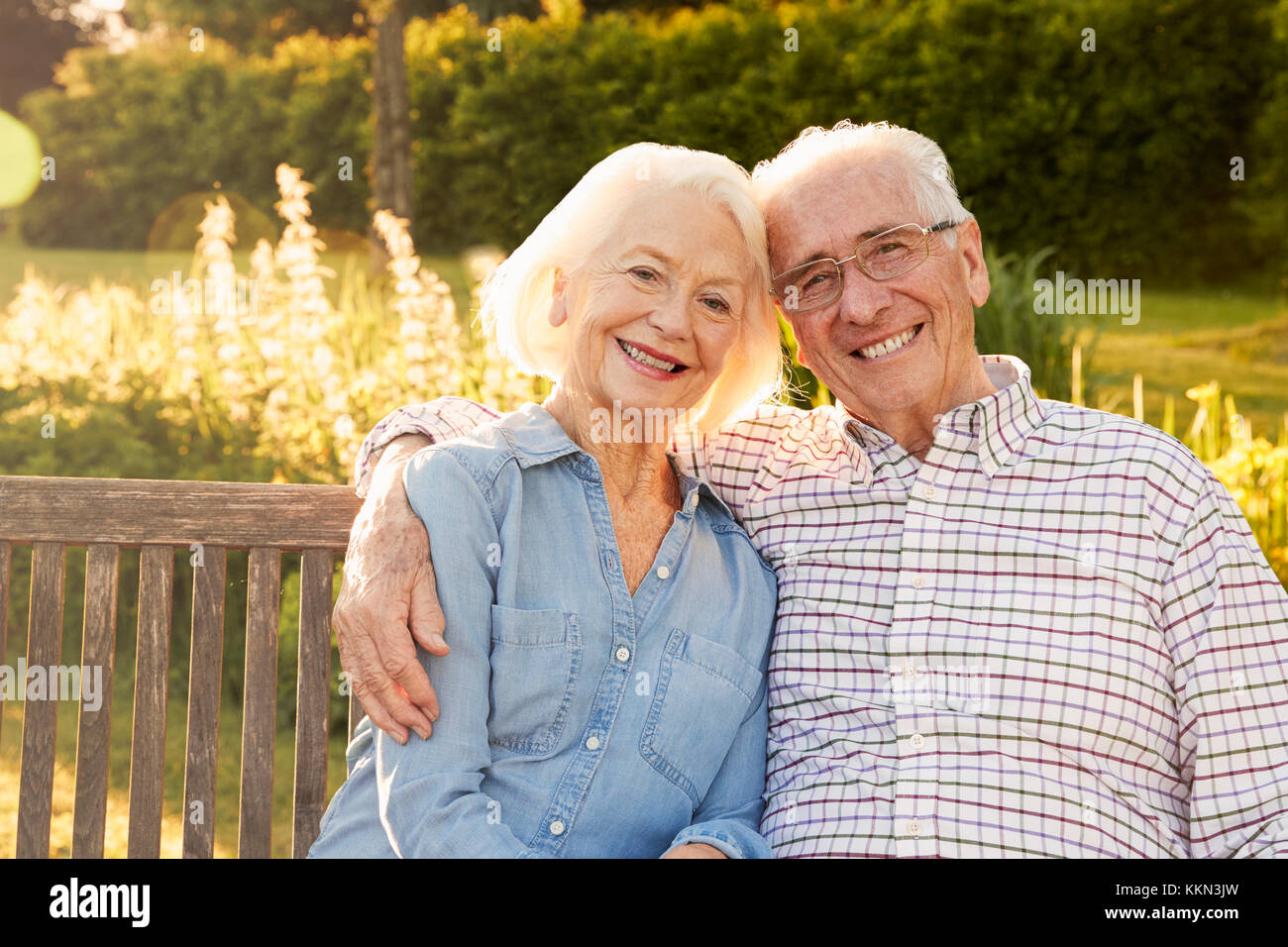 Senior Couple Sitting On Garden Bench In Evening Sunlight Stock Photo ...