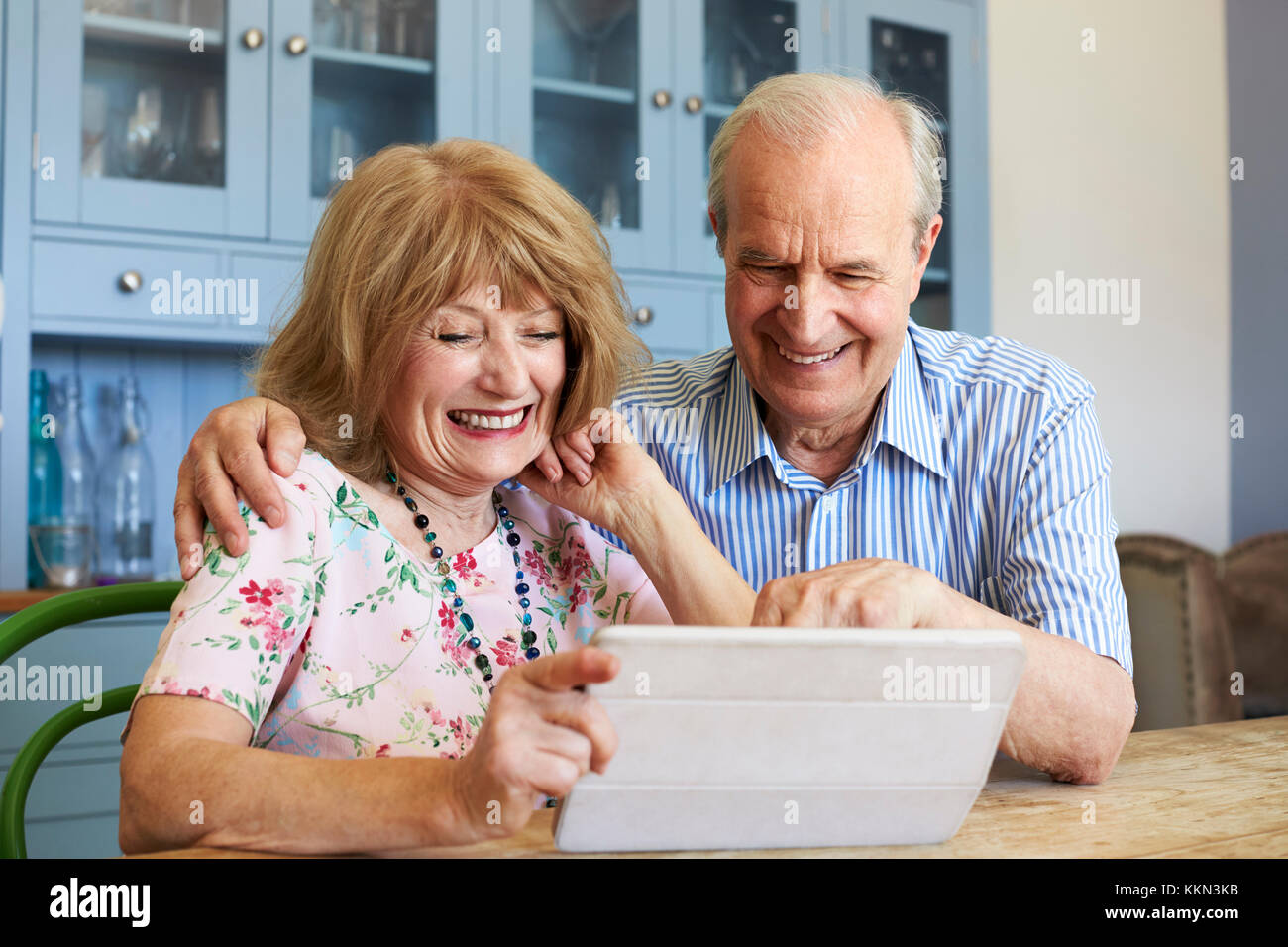 Senior Couple Sit At Home Using Digital Tablet Together Stock Photo