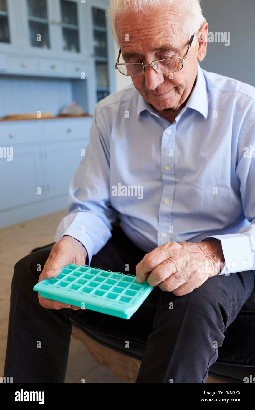 Senior Man At Home Using Pill Organiser For Medication Stock Photo