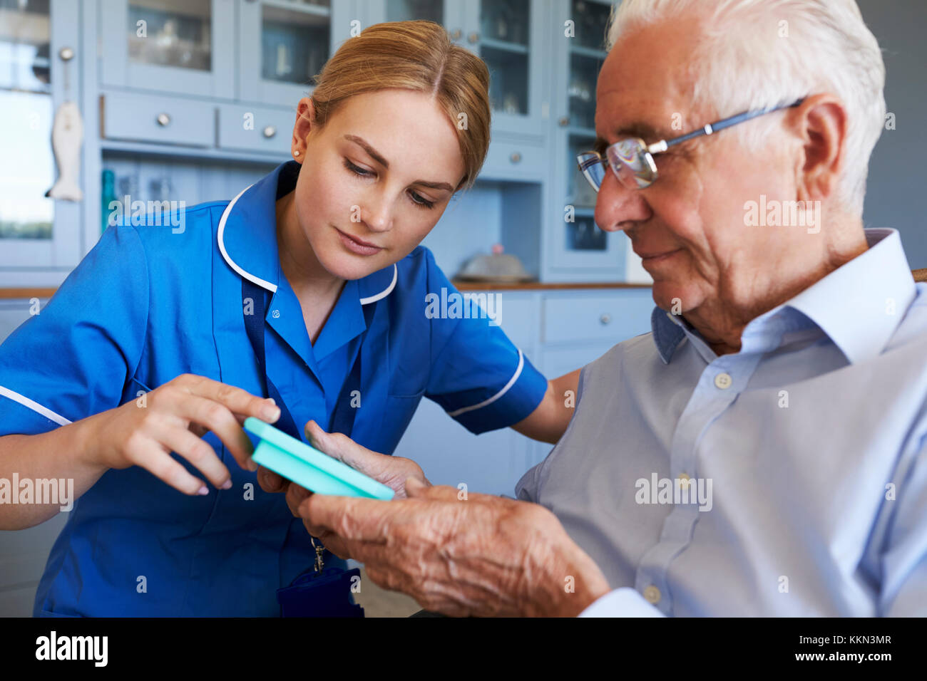 Nurse Helping Senior Man To Organize Medication On Home Visit Stock Photo