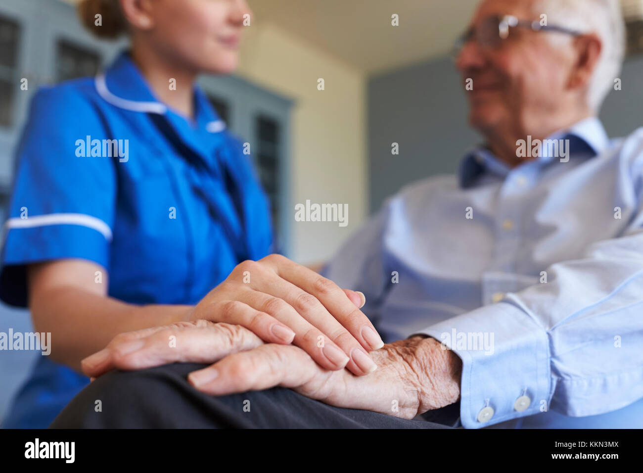 Nurse Talking With Senior Man Sitting In Chair On Home Visit Stock Photo