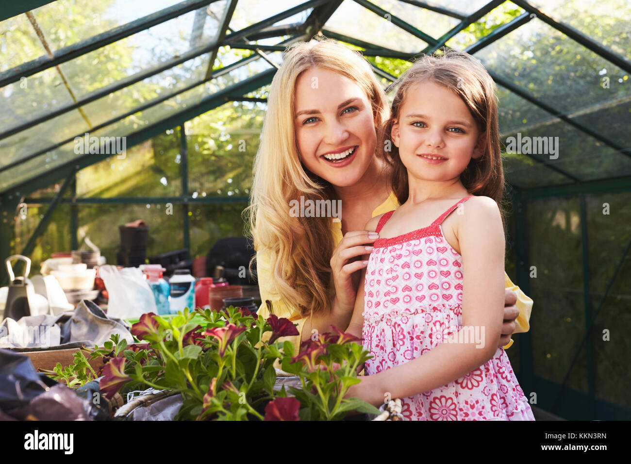 Portrait Of Mother And Daughter Planting Basket In Greenhouse Stock Photo