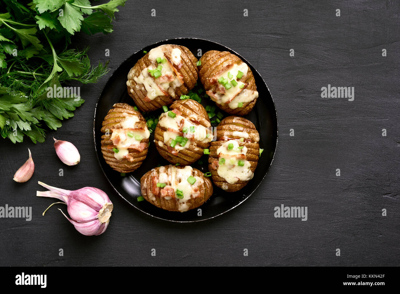 Baked stuffed potatoes with bacon, green onion and cheese on black background with copy space. Top view, flat lay. Stock Photo