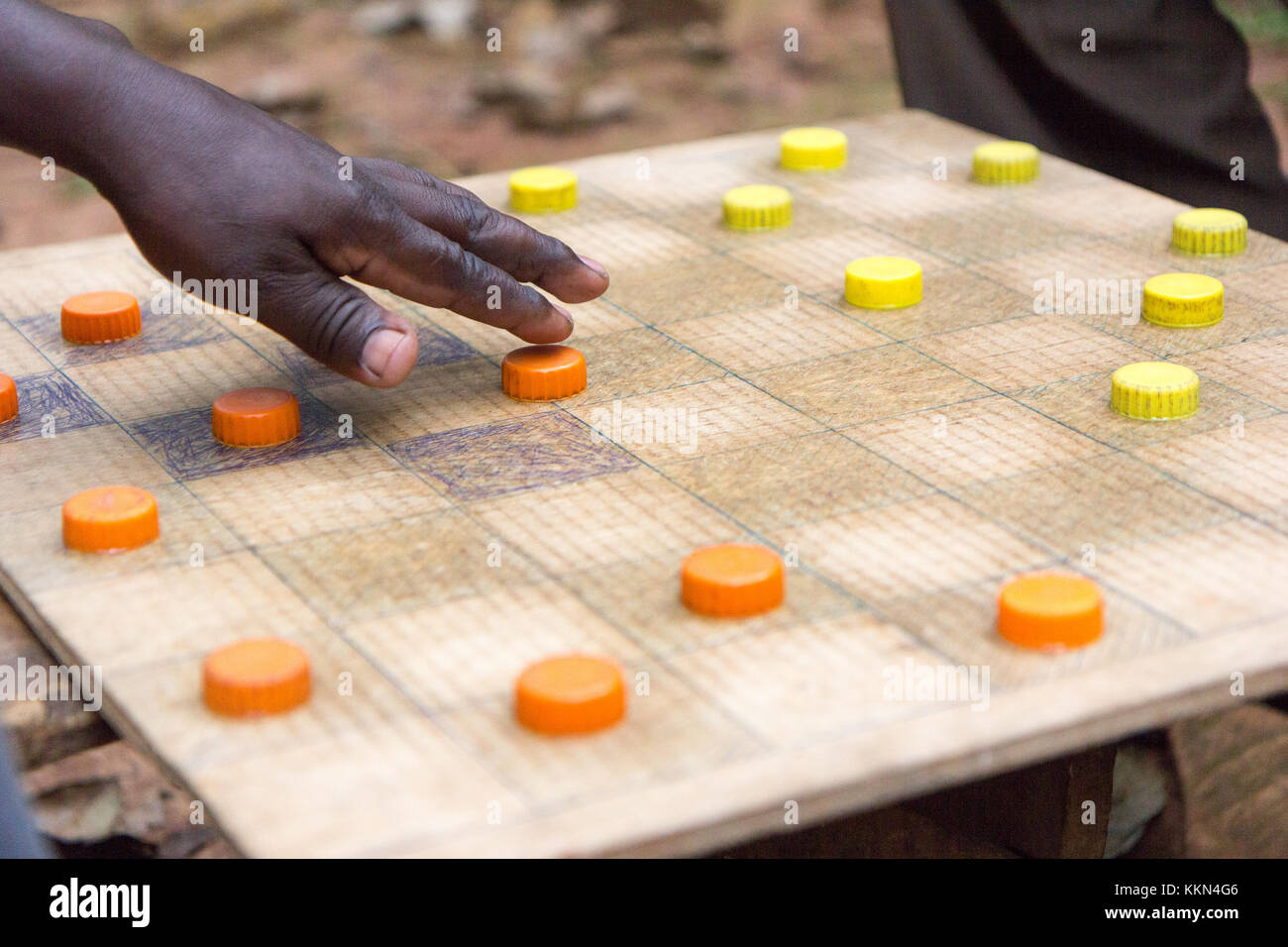 Ugandan men playing draughts (checkers) with plastic bottle lids serving as pieces. Stock Photo