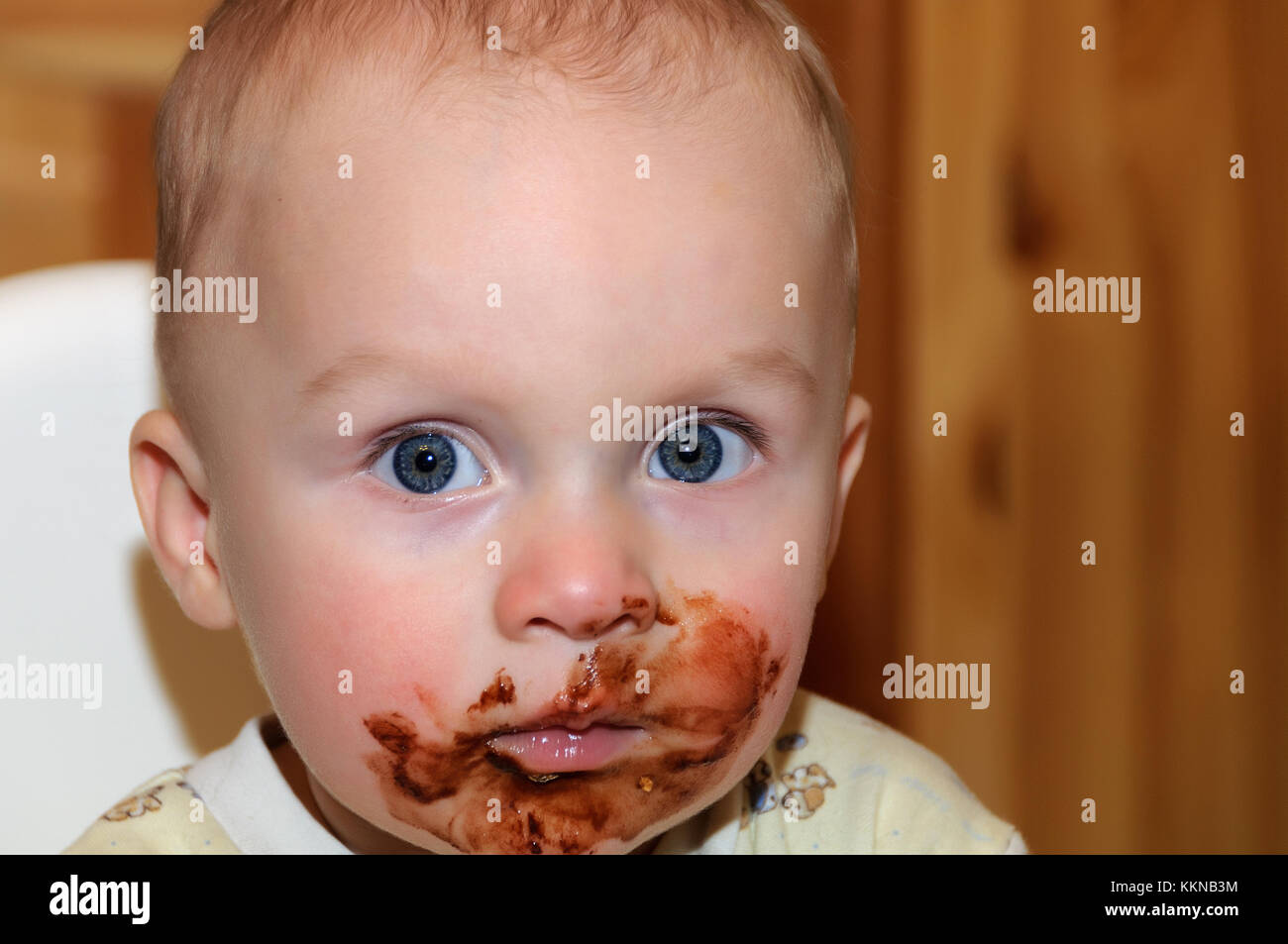 Portrait of a child in the highchair. His face and hands smeared with chocolate Stock Photo