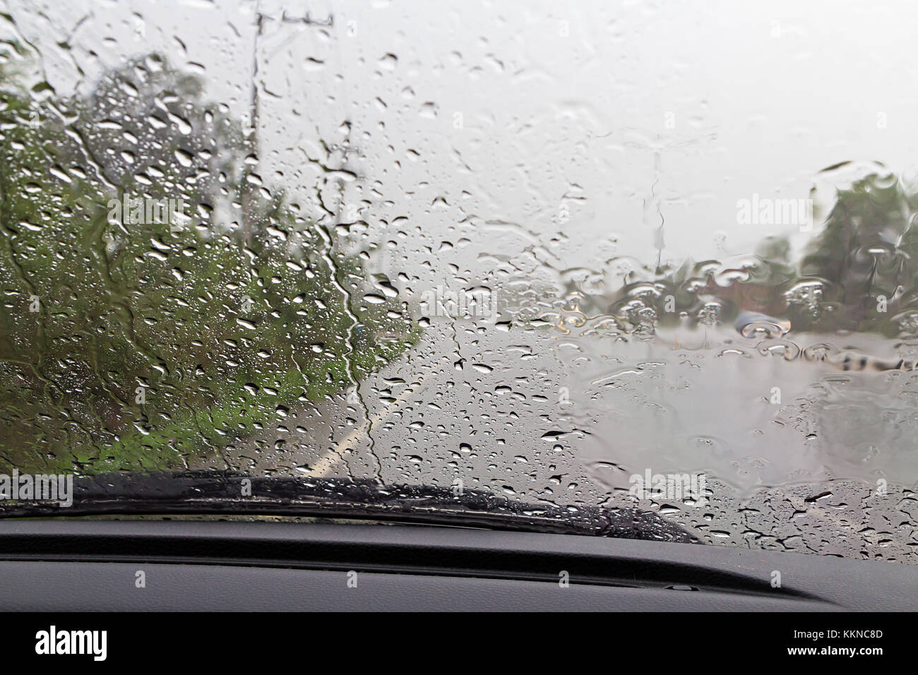 Road view through car windshield with rain drops, Driving in rain Stock
