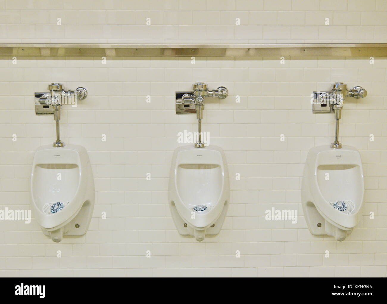 Closeup of three white urinals in men's bathroom, design of white