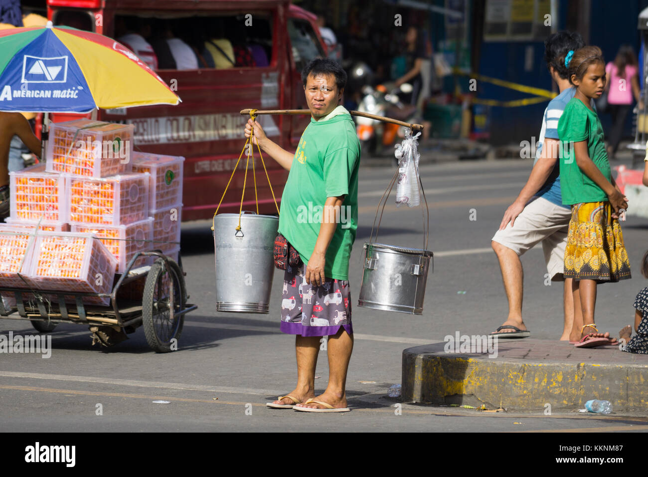 A Filipino man carrying two metal buckets which contain a popular sweet snack food commonly known as Taho Stock Photo