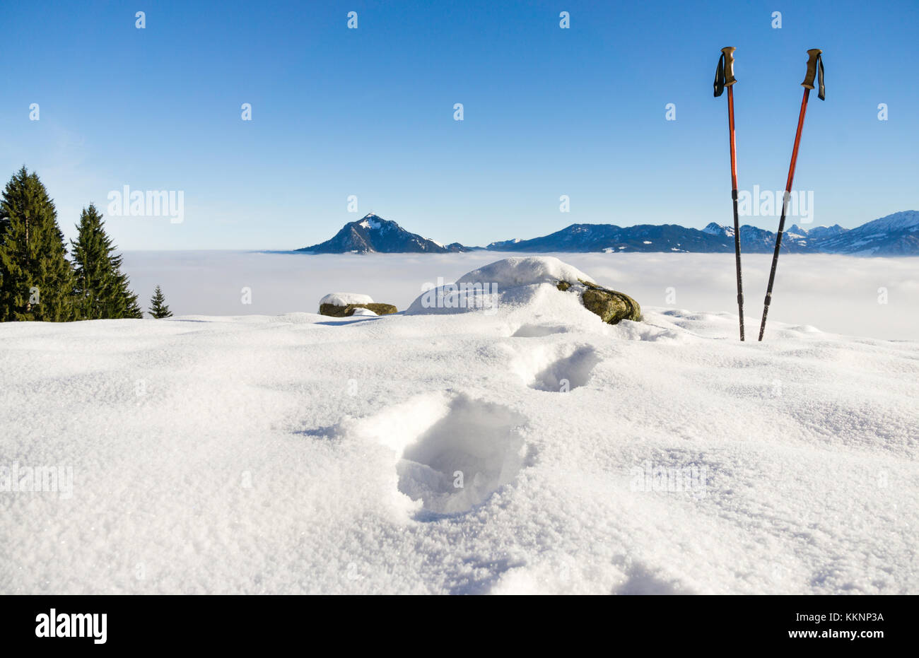 Pair of hiking sticks and footprints in snow. Sporting activity in mountains winter landscape. Allgau, Bavaria, Germany. Stock Photo