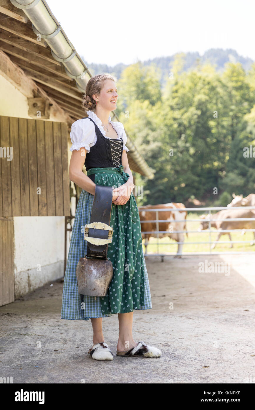 Farmer with dirndl carrying a cowbell Stock Photo