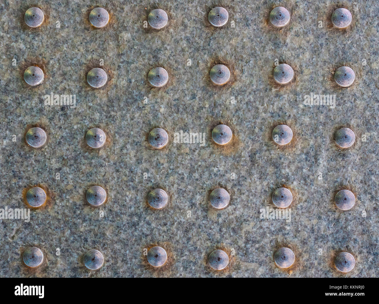 Front symmetric view of the texture of granite slab with round metal ...