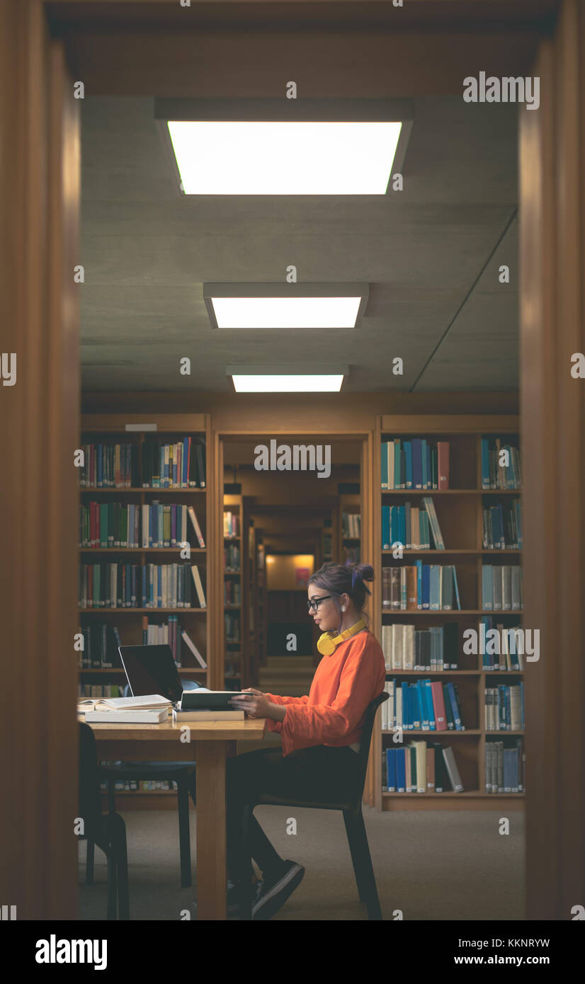 Girl reading book in library Stock Photo - Alamy