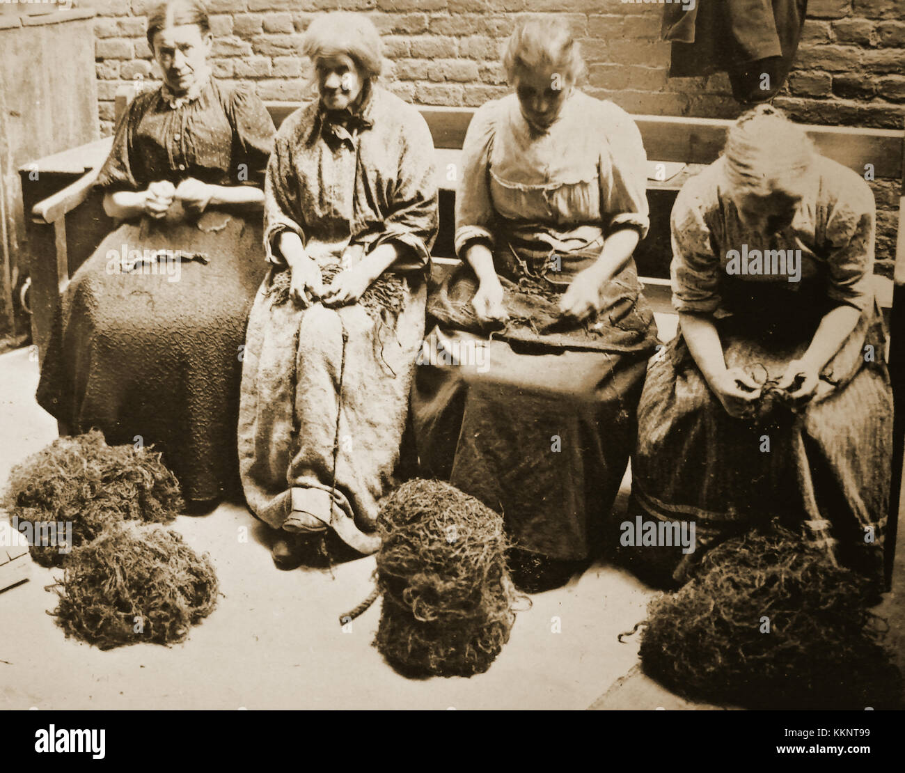Scottish women picking oakum (loose fibre obtained by untwisting old rope ) used   in caulking wooden sailing ships) - Probably in a  Victorian workhouse or correction house Stock Photo