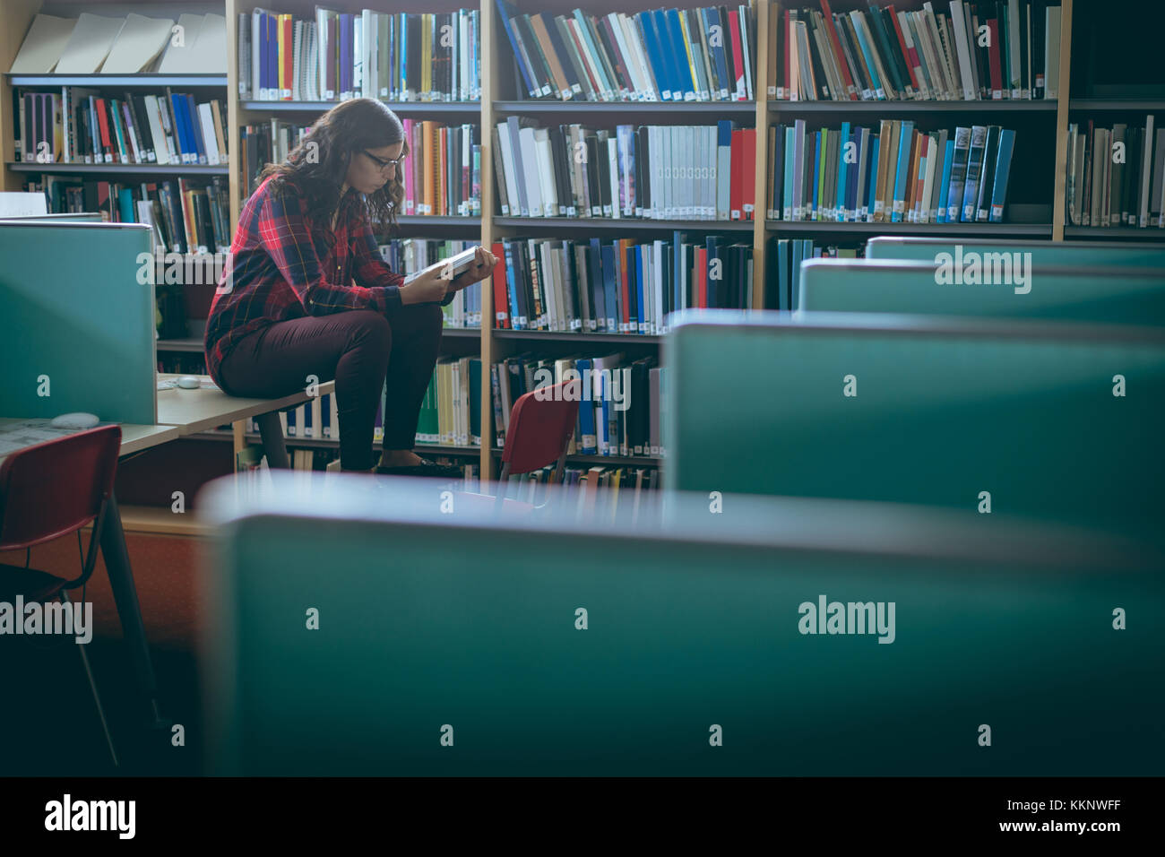 Girl reading book in library Stock Photo - Alamy