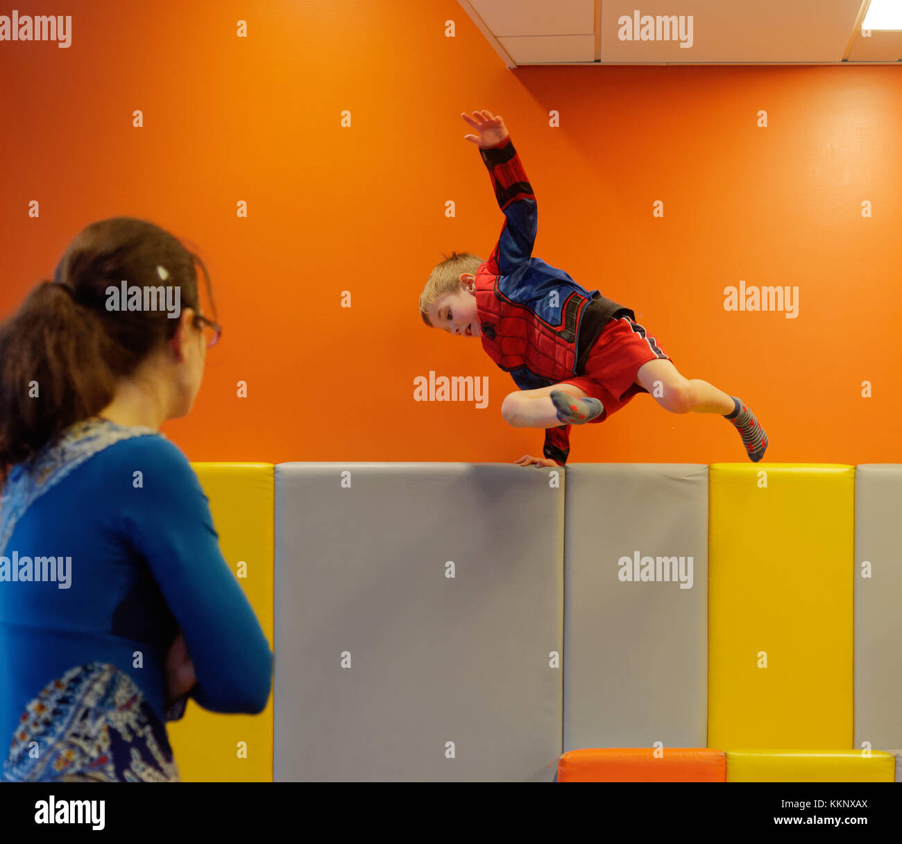 A little boy (5 yrs old) jumping in a padded play area Stock Photo