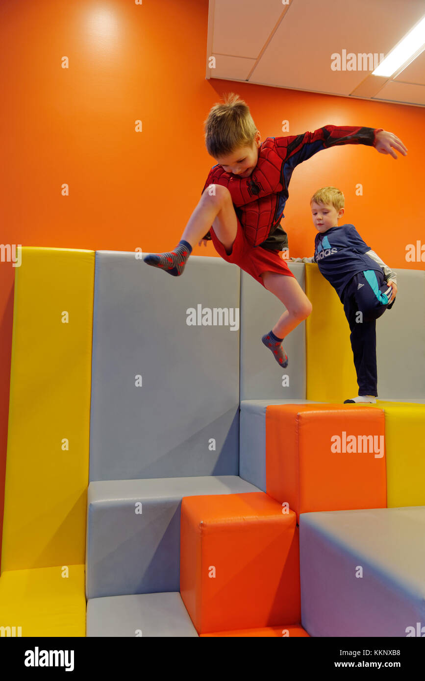 A little boy (5 yrs old) jumping in a padded play area Stock Photo