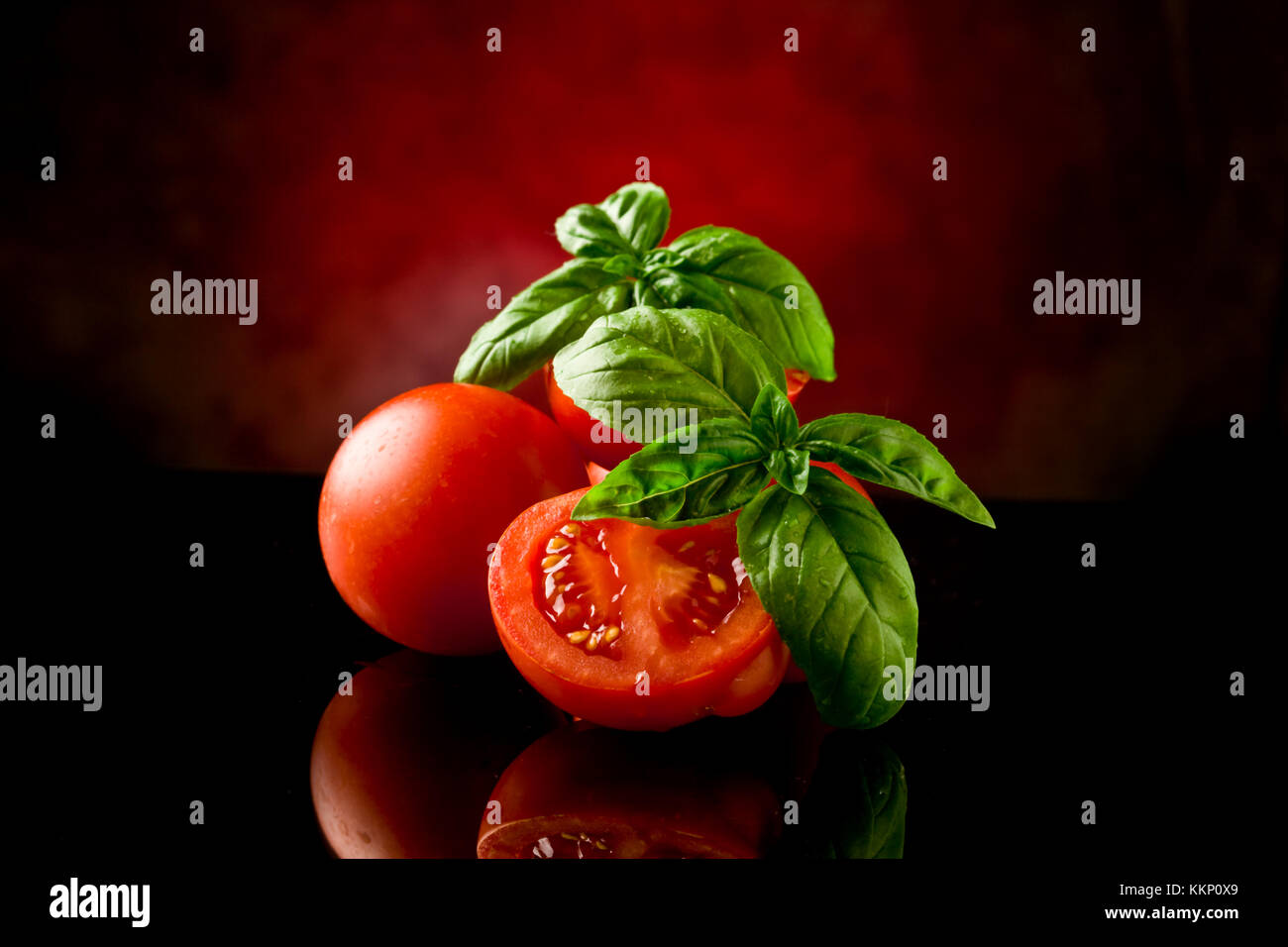photo of fresh sliced tomatoes with basil on glass table with spot ...