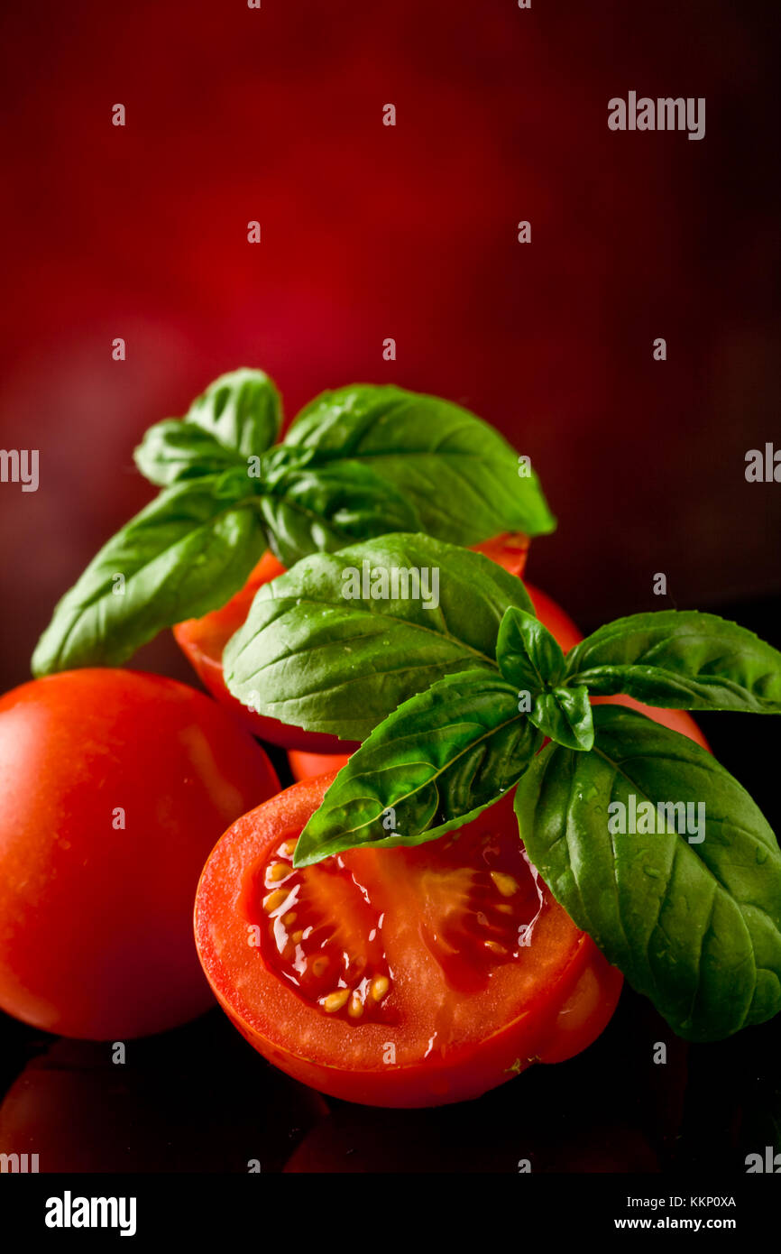 photo of fresh sliced tomatoes with basil on glass table with spot ...