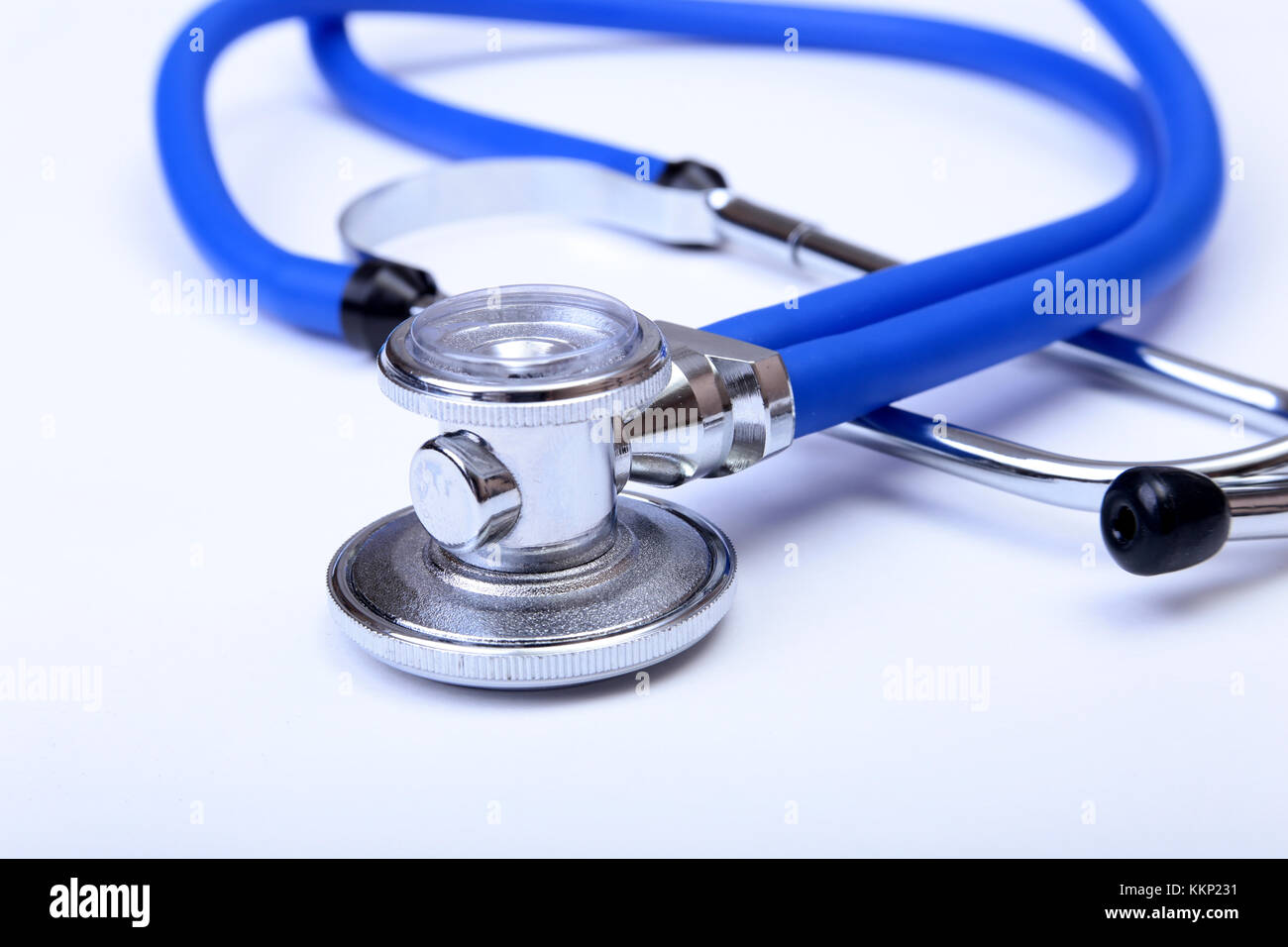 Medical stethoscope head lying on blue doctor uniform closeup. Medical
