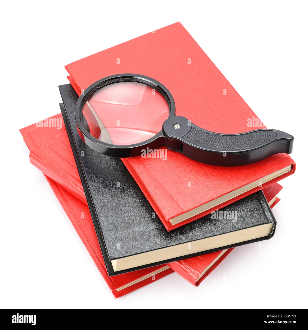 Large magnifier on book stack isolated on white. Stock Photo