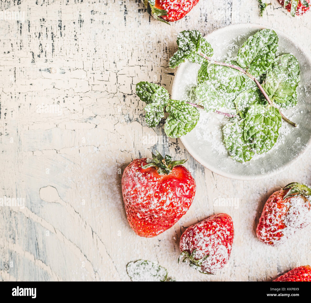 Fresh sliced Strawberries with powdered sugar and mint leaves in bowl ...