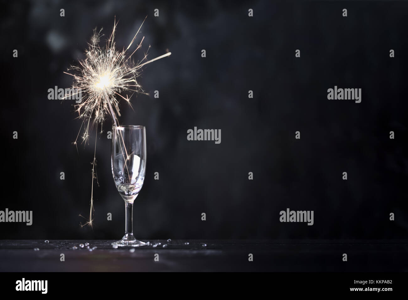 Champagne glass with lit sparkler against a dark background Stock Photo