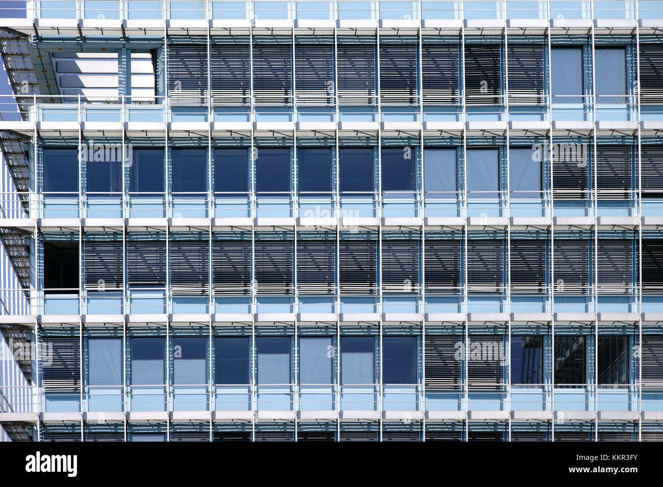 The modern facade of an office building with rows of windows and metal Venetian blinds. Stock Photo